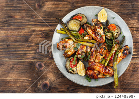Spicy grilled chicken wings on wooden surface. 124488987