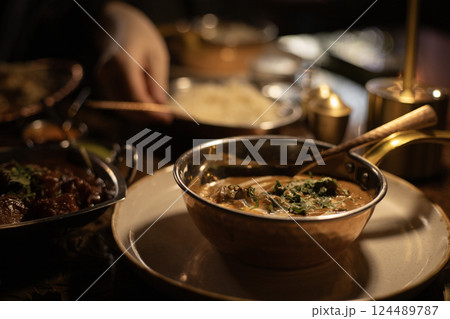 Indian dish chicken curry, in the background a man's hand is pouring rice Indian dish chicken curry, in the background a man's hand is pouring rice 124489787