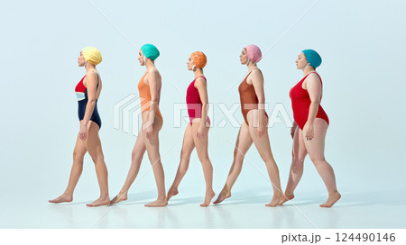 Women in vintage swimsuits and swim caps walking in line in rhythmical motion over light blue background Women in vintage swimsuits and swim caps walking in line in rhythmical motion over light blue background 124490146