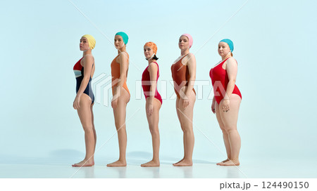 Five young women in retro swimsuits and colorful swim caps posing sideways in line over white background. Five young women in retro swimsuits and colorful swim caps posing sideways in line over white background. 124490150