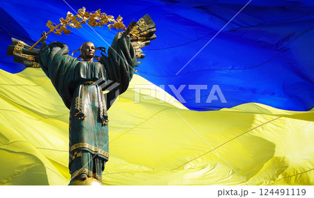 Kyiv, Ukraine July 20, 2020: A monument dedicated to the independence of Ukraine against the background of the largest Flag of Ukraine 124491119
