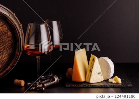 A refined selection of aged cheeses presented on a board, accompanied by a glasses of wine A refined selection of aged cheeses presented on a board, accompanied by a glasses of wine 124491180