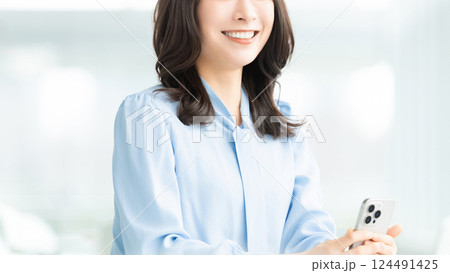 スマートフォンを持つ笑顔の女性・ビジネスウーマン スマートフォンを持つ笑顔の女性・ビジネスウーマン 124491425