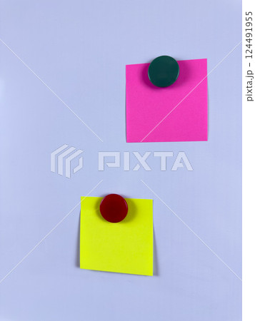Pink and yellow sticky notes secured with magnets on a whiteboard ideal for reminders planning and organization in office school or home environments enhancing efficiency and creativity 124491955