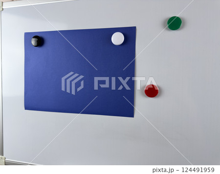 Large blue paper note pinned to whiteboard with magnets. Ideal for workspaces that require organization and planning for increased efficiency Large blue paper note pinned to whiteboard with magnets. Ideal for workspaces that require organization and planning for increased efficiency 124491959