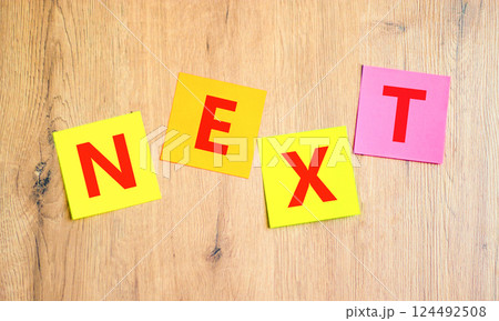 Next symbol. Concept word Next on beautiful colored paper. Beautiful wooden table wooden background. Business, lifestyle, support and next concept. Copy space. 124492508