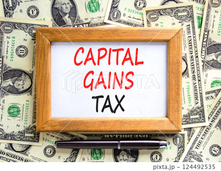 Capital gains tax symbol. Concept words Capital gains tax on beautiful wooden picture frame. Black pen. Beautiful background from dollar bills. Business and capital gains tax concept. Copy space. 124492535