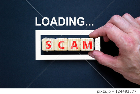 Scam symbol. Concept word Loading Scam on beautiful wooden blocks. Businessman hand. Beautiful black table black background. Business, lifestyle, support and scam concept. Copy space. Scam symbol. Concept word Loading Scam on beautiful wooden blocks. Businessman hand. Beautiful black table black background. Business, lifestyle, support and scam concept. Copy space. 124492577