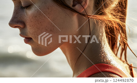 Young woman or girl with clear freckled skin in warm morning sunlight on sea beach. Female portrait in profile on the street. People workout outdoors. This is AI-generated item 124492870