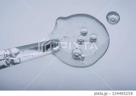 Pipette with serum on a blue background. Product texture. 124493259