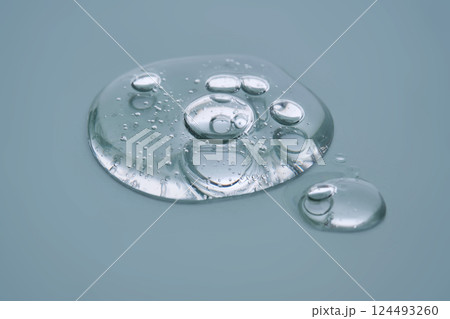 Textured round drop of serum with bubbles on dark green background. Textured round drop of serum with bubbles on dark green background. 124493260