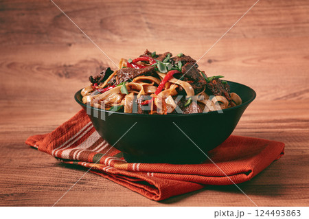 Udon noodles with beef in Mongolian style, with green onions and vegetables, homemade, on a wooden table, Udon noodles with beef in Mongolian style, with green onions and vegetables, homemade, on a wooden table, 124493863