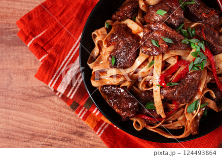 Udon noodles with beef in Mongolian style, with green onions and vegetables, homemade, on a wooden table, 124493864