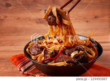 Udon noodles with beef in Mongolian style, with green onions and vegetables, homemade, on a wooden table, 124493867