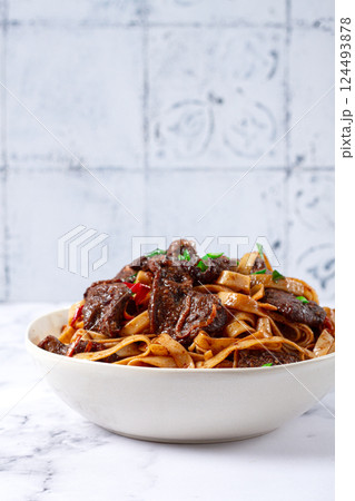 Udon noodles with Mongolian beef, green onions and vegetables, in a white plate, on a light background, homemade, no people, 124493878