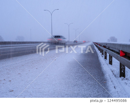 Snowy highway conditions with vehicles navigating during a winter storm 124495086