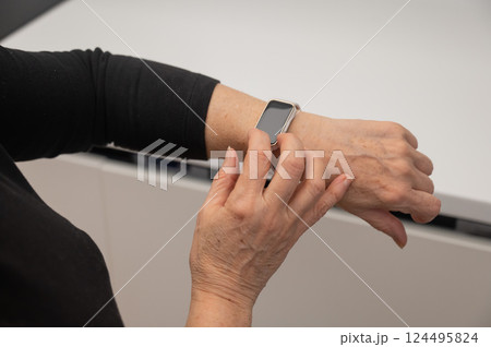 Elderly Caucasian woman looking at smart watch. Close-up of hands.  124495824