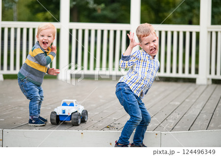 Two Boys Making Funny Faces and Playing Outdoors with Toy Car Two Boys Making Funny Faces and Playing Outdoors with Toy Car 124496349