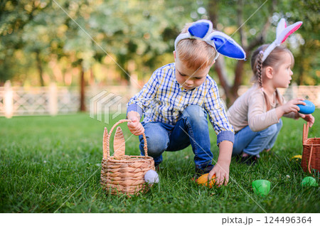 Children Hunting Easter Eggs in the Garden with Bunny Ears Children Hunting Easter Eggs in the Garden with Bunny Ears 124496364
