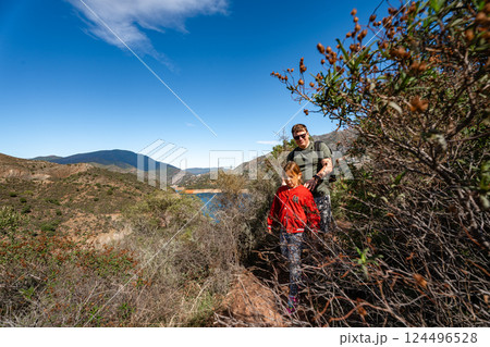 Father and daughter hiking in scenic mountain landscape on sunny day 124496528