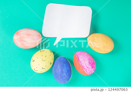 Colorful painted eggs with a speech bubble on a green background. 124497063