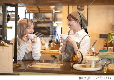 カウンターでコーヒーを飲みながら会話する2人の女性バリスタ 124497315