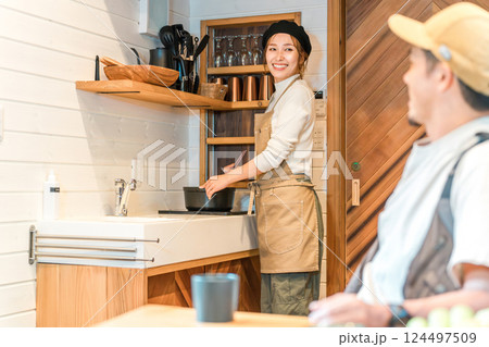 コテージ泊・家族旅行でミニキッチンで料理する妻と会話する夫 124497509