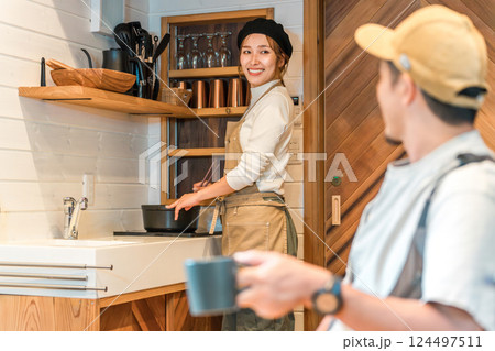 コテージ泊・家族旅行でミニキッチンで料理する妻と会話する夫 124497511