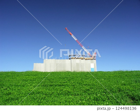 秋の江戸川土手越しに見るビル建設現場風景 124498136