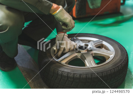 タイヤ空気圧を測定・タイヤに空気を入れる自動車整備士の手元 124498570