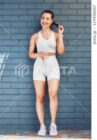 Fitness, cardio and woman with body workout idea training goals and water bottle for wellness lifestyle. Happy runner girl in sports fashion with healthy thinking, exercise motivation on a brick wall 124498887
