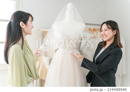 ウェディングプランナー,ドレスコーディネーターとドレス選びの打ち合わせをする女性 ウェディングプランナー,ドレスコーディネーターとドレス選びの打ち合わせをする女性 124498940