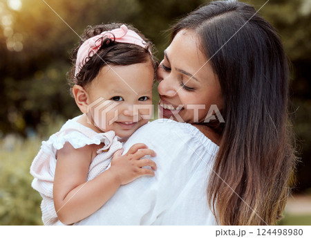 Happy mother with girl baby hug in a park with summer love, smile and care or growth development wellness. Happy latino mom with kid in portrait together nature outdoor for mothers day with happiness 124498980
