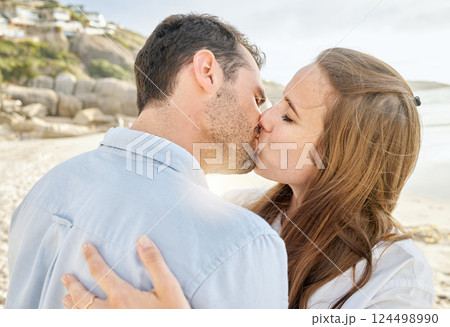 Happy, kiss and couple on a beach with love from engagement announcement or anniversary. Happiness, relax and care of a woman and man together by the sea and ocean outdoor with commitment Happy, kiss and couple on a beach with love from engagement announcement or anniversary. Happiness, relax and care of a woman and man together by the sea and ocean outdoor with commitment 124498990