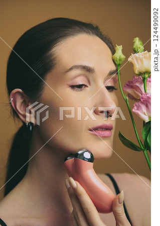 Skin care routine featuring cleansing device and fresh flowers indoors Skin care routine featuring cleansing device and fresh flowers indoors 124499092