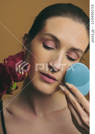 Skincare routine featuring facial cleansing brush and rose flower at home 124499159