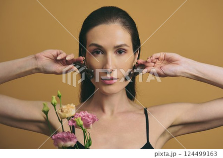 Woman holding flowers and chocolate against warm background in indoor setting Woman holding flowers and chocolate against warm background in indoor setting 124499163