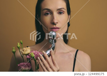 Woman holding a flower bouquet and a chrome object in warm lighting 124499175