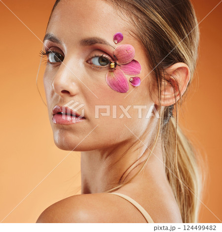 Model, eye and flower for makeup at studio for portrait, art and natural beauty. Girl, eyes and flowers with floral organic cosmetics on skin with shine, glow and healthy face with orange backdrop Model, eye and flower for makeup at studio for portrait, art and natural beauty. Girl, eyes and flowers with floral organic cosmetics on skin with shine, glow and healthy face with orange backdrop 124499482