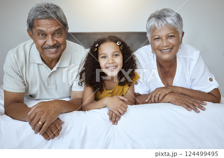 Happy, grandparents and child lying on bed with smile for family bonding, retirement and relax at home. Portrait of little girl, grandma and grandpa smiling in bedroom relaxing together for childcare Happy, grandparents and child lying on bed with smile for family bonding, retirement and relax at home. Portrait of little girl, grandma and grandpa smiling in bedroom relaxing together for childcare 124499495