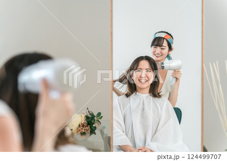 美容室・ヘアサロンでドライヤーで髪を乾かす・ブローしてもらうアジア人女性 124499707