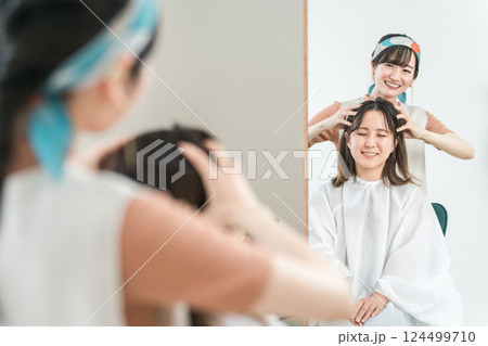 美容室・ヘアサロンに来た客にヘッドスパ・マッサージをする美容師・理容師のアジア人女性 美容室・ヘアサロンに来た客にヘッドスパ・マッサージをする美容師・理容師のアジア人女性 124499710