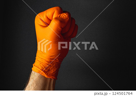 Orange-gloved fist symbolizes strength and resolve Orange-gloved fist symbolizes strength and resolve 124501764