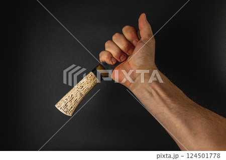 Hand gripping a handcrafted object against a dark backdrop 124501778