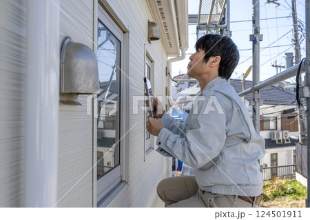戸建て家屋の外壁修繕工事進行状況を確認する男性 戸建て家屋の外壁修繕工事進行状況を確認する男性 124501911