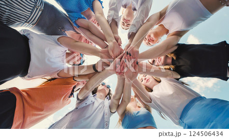 School friends come together in a circle, intertwining their hands to represent unity, teamwork, and collaboration 124506434