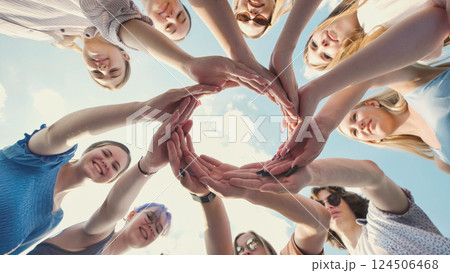 School friends join hands in a circle against a blue sky, representing unity, teamwork, and friendship School friends join hands in a circle against a blue sky, representing unity, teamwork, and friendship 124506468