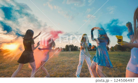Young women enjoying the holi festival, throwing colored powder in the air at sunset, embracing friendship and unity 124506497