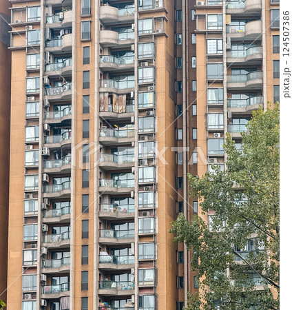 Modern residential building showcasing balconies and air conditioning units in a bustling urban area. 124507386