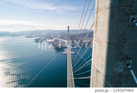 Aerial view of the cable-stayed bridge in Vladivostok, highlighting its towering pillars and cables against a backdrop of clear skies and calm waters Aerial view of the cable-stayed bridge in Vladivostok, highlighting its towering pillars and cables against a backdrop of clear skies and calm waters 124507464